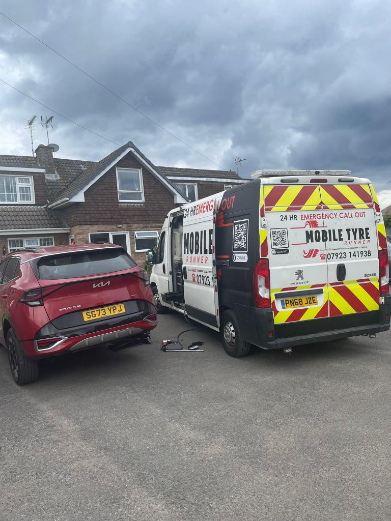 Mobile Tyre Runner van on a home driveway next to a red Kia having its tyre changed