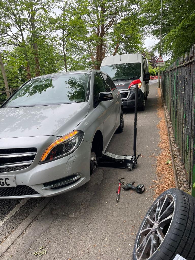 Wheel removed from a Mercedes at the roadside with tools on the ground