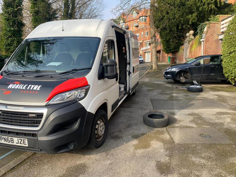 Mobile Tyre Runner van parked beside a car having a tyre changed on a residential road